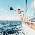 Man enjoying freedom by jumping into the ocean from a sailboat in Greece.