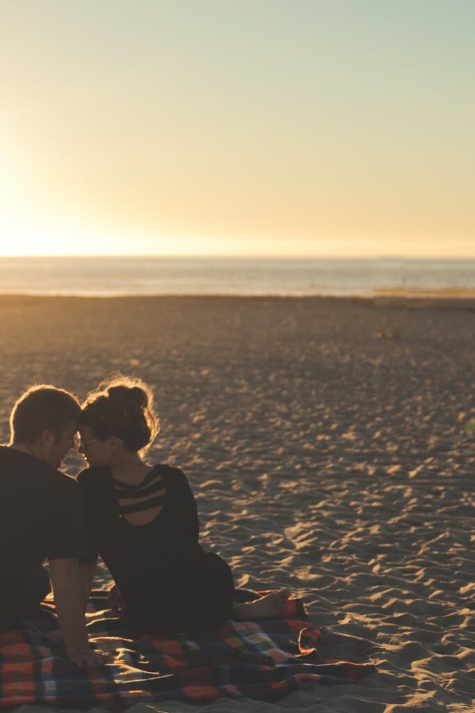 A couple enjoys sunset together on a sandy beach, capturing a moment of love and togetherness.